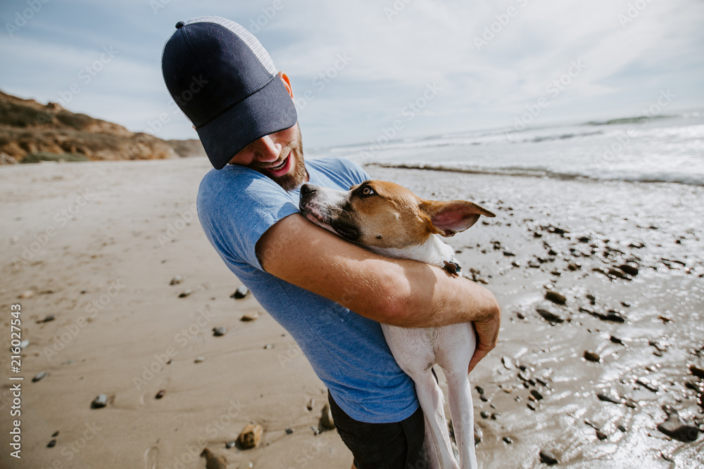 Fotografie Man playing with dog at ocean beach