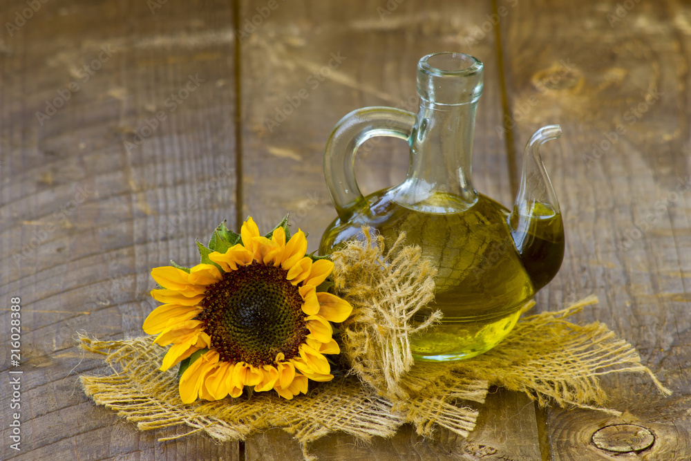 Glass bottle with sunflower oil and sunflower on wooden background Glass bottle with sunflower oil and sunflower on wooden background