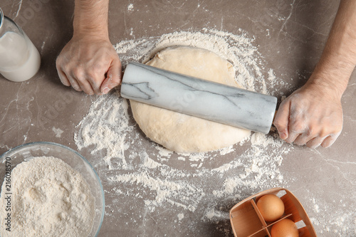 Man rolling dough for pizza on table