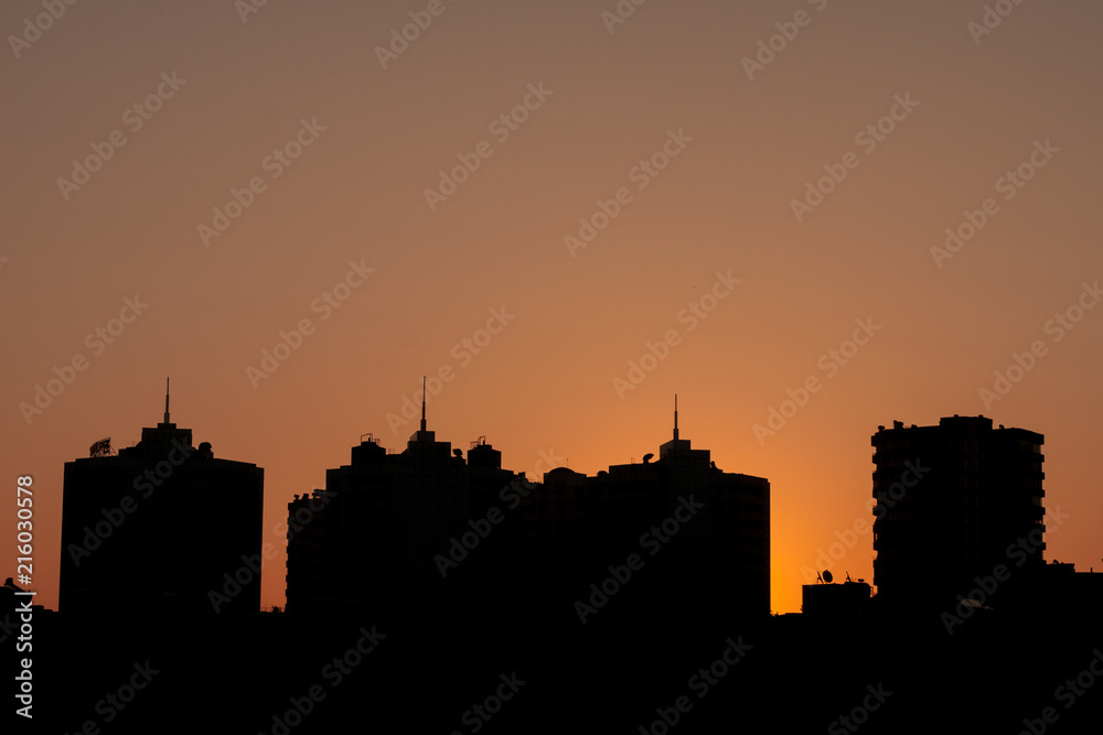 Dark buildings silhouettes at the sunset with orange sky