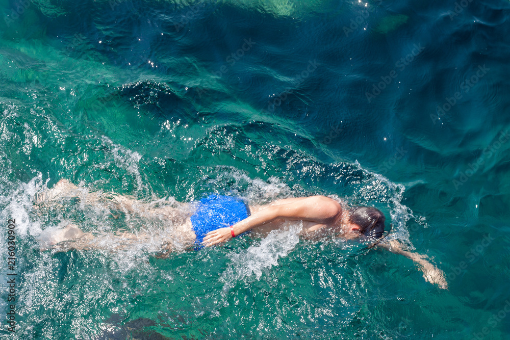 Young man swimming at blue sea