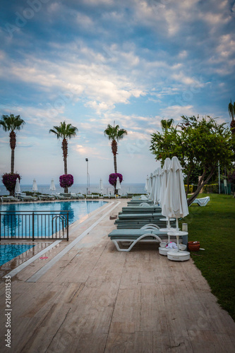 Obraz na plátně HDR pol view at summer evening in Turkey, with pool, chaise lounges, palms and b