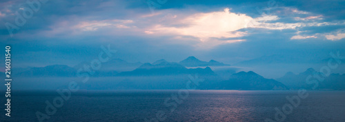 panorama view to the mountines and sea at blue hour, with beautiful rays of light  throw the clouds © Nikita Khrebtov