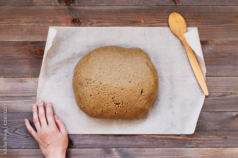 The piece of fresh dough for gingerbread and female hand The piece of fresh dough for gingerbread and female hand