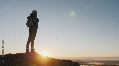 Obraz na plátne Crane shot: A woman traveler stands on top of a mountain, looks at the beautiful