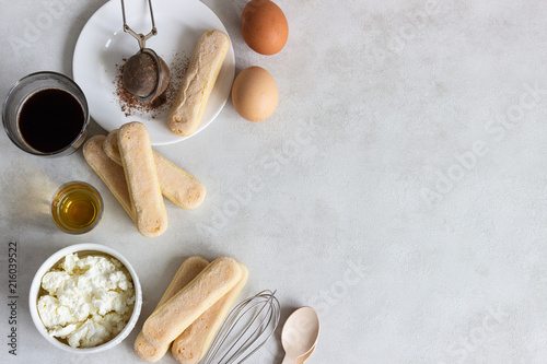 Ingredients for making traditional Italian dessert Tiramisu: mascarpone cheese, savoiardi, cocoa, coffee, brandy and eggs on light grey background. Copy space