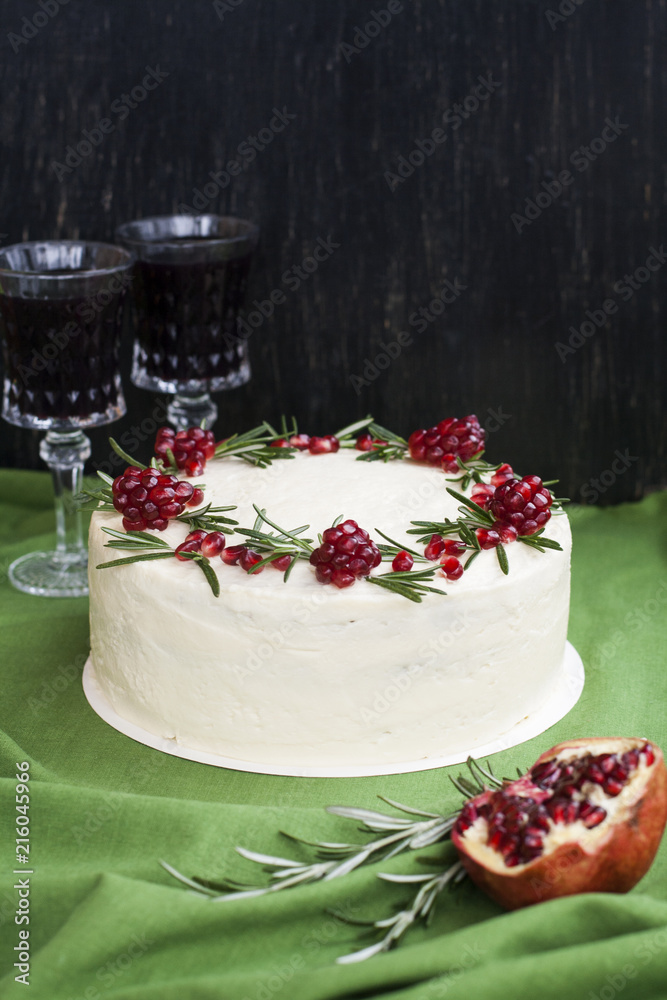 Naklejka premium Chocolate cake with berry cream, white cheese cream, pomegranate berries and rosemary branches. Two glasses of red wine. Idea for a birthday cake or for a wedding cake.