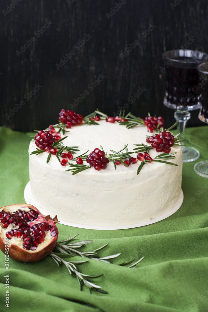 Naklejka premium Chocolate cake with berry cream, white cheese cream, pomegranate berries and rosemary branches. Two glasses of red wine. Idea for a birthday cake or for a wedding cake.