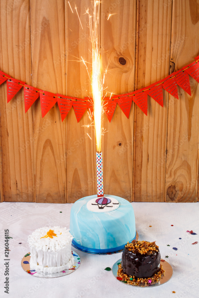 Tortas de cumpleaños con bengala encendida y fondo con banderines rojos  Stock Photo