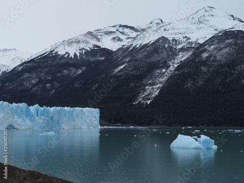 Glaciar junto a montaña nevada y pequeño iceberg flotando en el lago