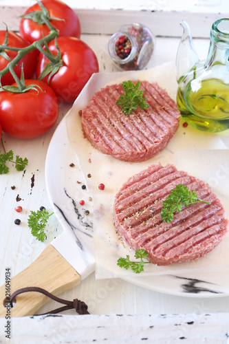 Two raw patty, olive oil and bunch of tomatoes