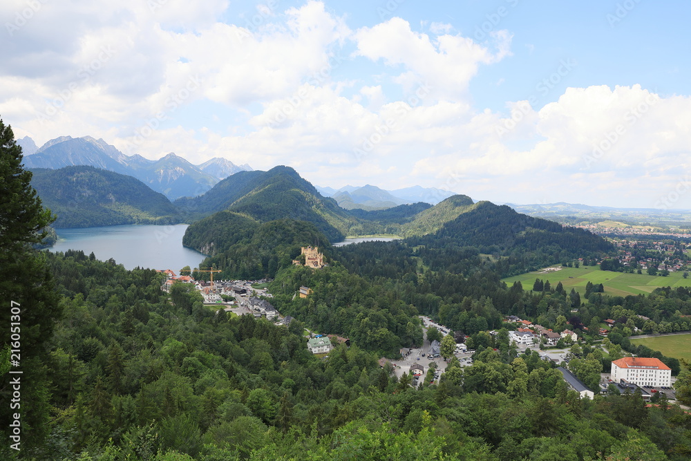 The picturesque foothills of the Alps, the lake surrounded with the low rocks overgrown with the dense wood.