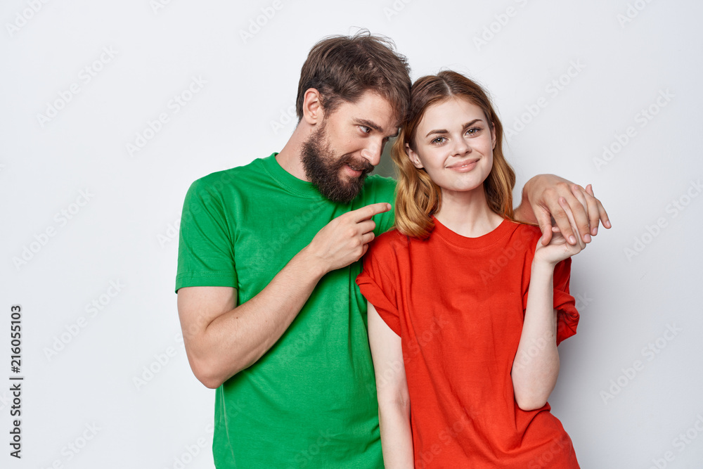 young couple in colored t-shirts on a light background young couple in colored t-shirts on a light background