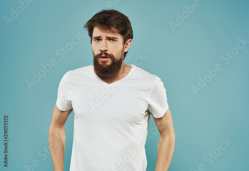 a man with a beard in a white T-shirt on a blue background