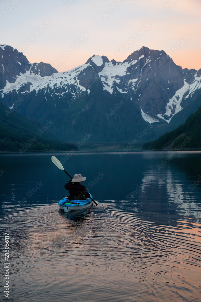 Adventurous man kayaking in the water surrounded by the Beautiful Canadian Mountain Landscape. Taken in Jones Lake, near Hope, East of Vancouver, BC, Canada. Adventurous man kayaking in the water surrounded by the Beautiful Canadian Mountain Landscape. Taken in Jones Lake, near Hope, East of Vancouver, BC, Canada.