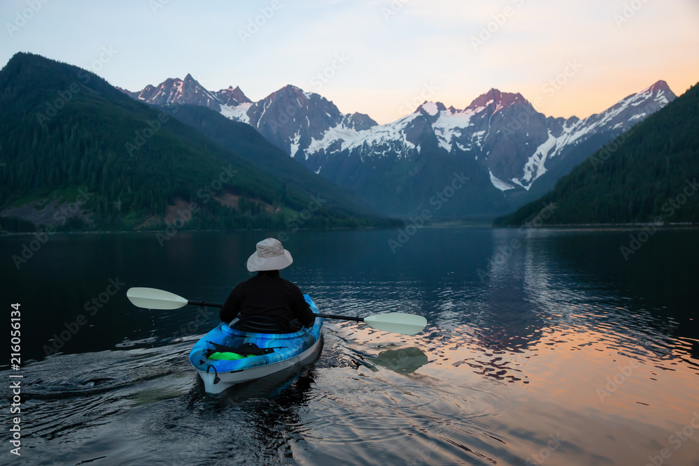 Adventurous man kayaking in the water surrounded by the Beautiful Canadian Mountain Landscape. Taken in Jones Lake, near Hope, East of Vancouver, BC, Canada. Adventurous man kayaking in the water surrounded by the Beautiful Canadian Mountain Landscape. Taken in Jones Lake, near Hope, East of Vancouver, BC, Canada.