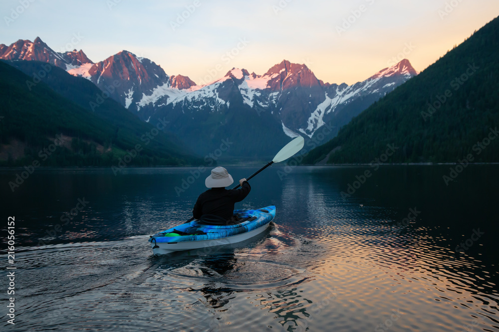 Adventurous man kayaking in the water surrounded by the Beautiful Canadian Mountain Landscape. Taken in Jones Lake, near Hope, East of Vancouver, BC, Canada.