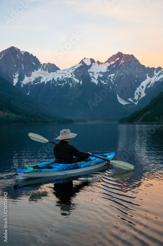 Adventurous man kayaking in the water surrounded by the Beautiful Canadian Mountain Landscape. Taken in Jones Lake  near Hope  East of Vancouver  BC  Canada.
