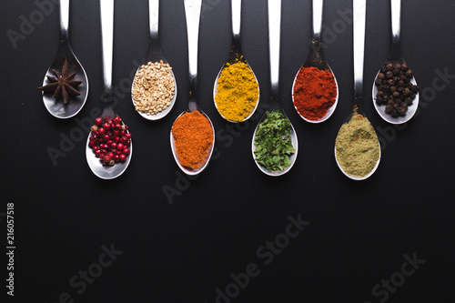 Fototapeta Naklejka Na Ścianę i Meble -  Spices and condiments for cooking on a black background, the image has a space available to add texts