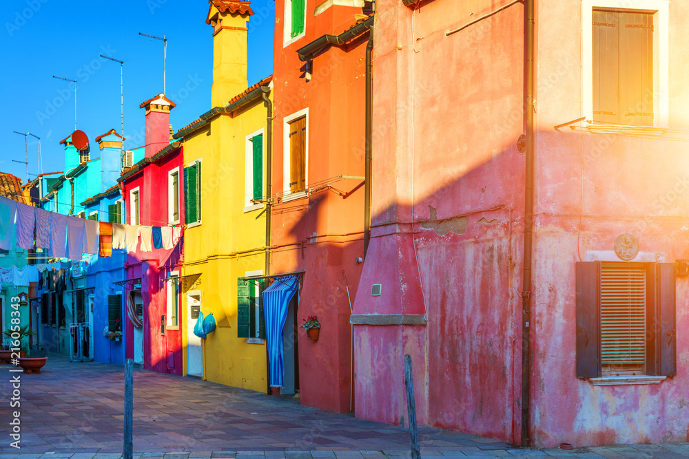 Fototapeta premium Street with colorful buildings in Burano island, Venice, Italy. Architecture and landmarks of Burano, Venice postcard. Scenic canal and colorful architecture in Burano island near Venice, Italy