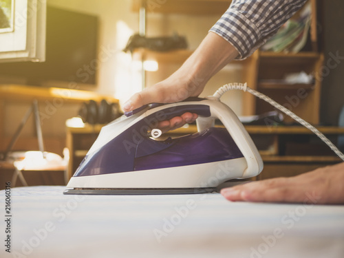 close up maid hand in the hotel ironing clothes in hotel room on white table