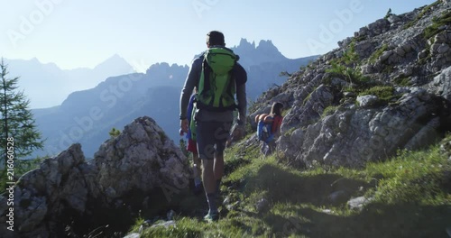 Four friends walking along hiking trail path. Group of friends people summer adventure journey in mountain nature outdoors. Travel exploring Alps, Dolomites, Italy. 4k slow motion 60p video