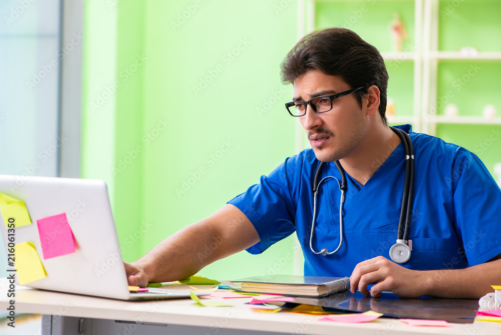 Young doctor sitting in hospital with many conflicting prioritie Young doctor sitting in hospital with many conflicting prioritie