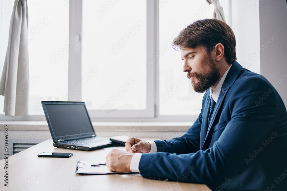 business man in profile works behind a laptop in the office business man in profile works behind a laptop in the office