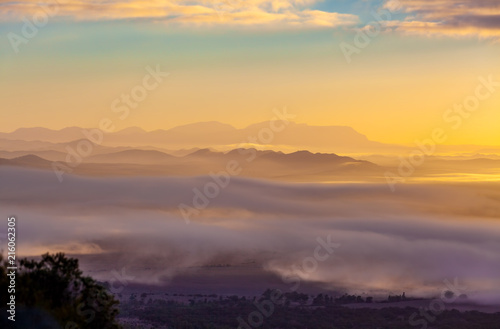 Mountain ridges protruding above low clouds at vivid sunset in Australia