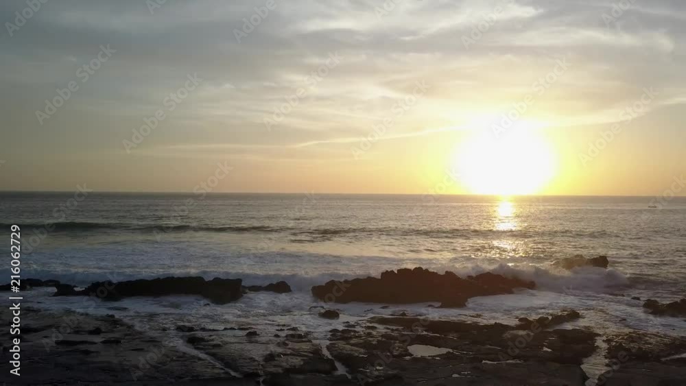 Drone soars sideways as ocean swell rolls in hits and splashes into rocks during sunset in Santa Teresa Costa Rica. Drone soars sideways as ocean swell rolls in hits and splashes into rocks during sunset in Santa Teresa Costa Rica.