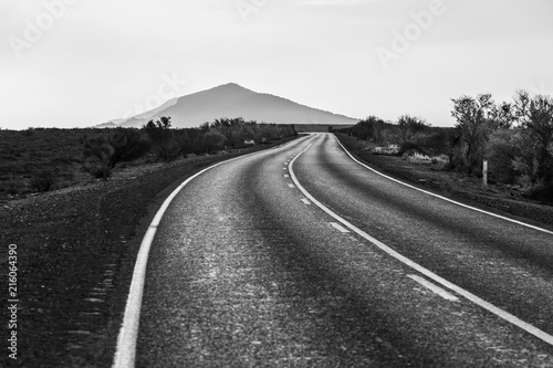 Winding road leading to a scenic mountain peak in black and white