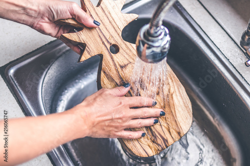 Teak wooden cutting board washing. Woman hands washing teak cutting board. photo
