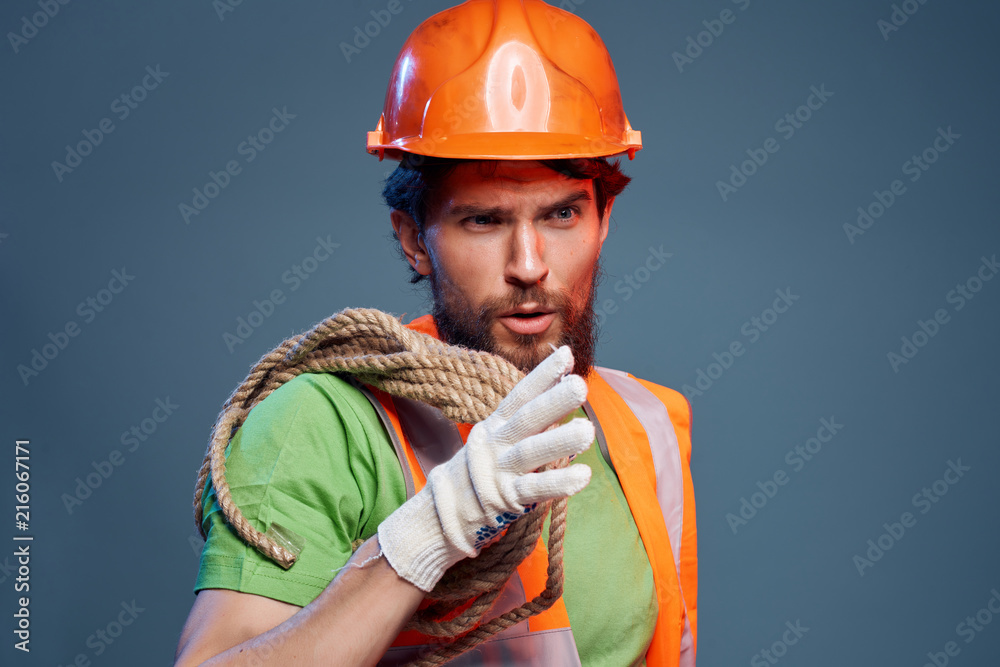 builder in a helmet with a rope on his shoulder builder in a helmet with a rope on his shoulder