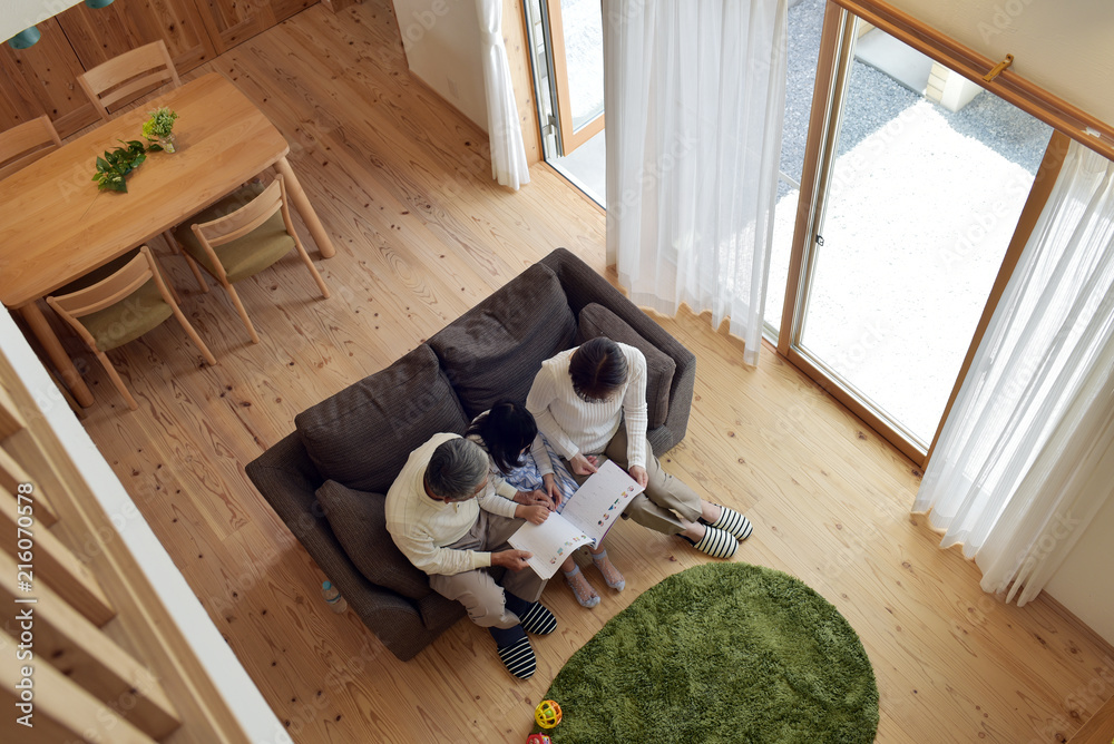 リビングで孫と絵本を読む祖父母 俯瞰 Stock Photo Adobe Stock