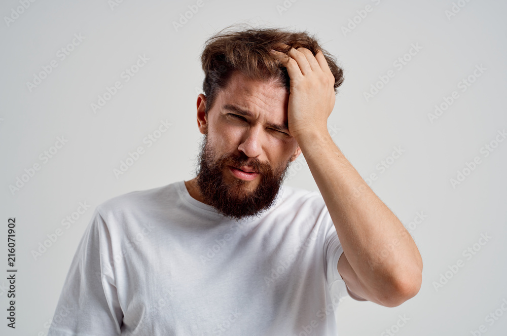 man with a beard holding his head in pain man with a beard holding his head in pain