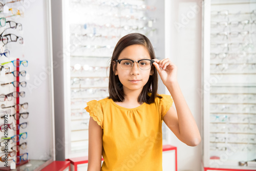 Little girl deciding to buy new glasses