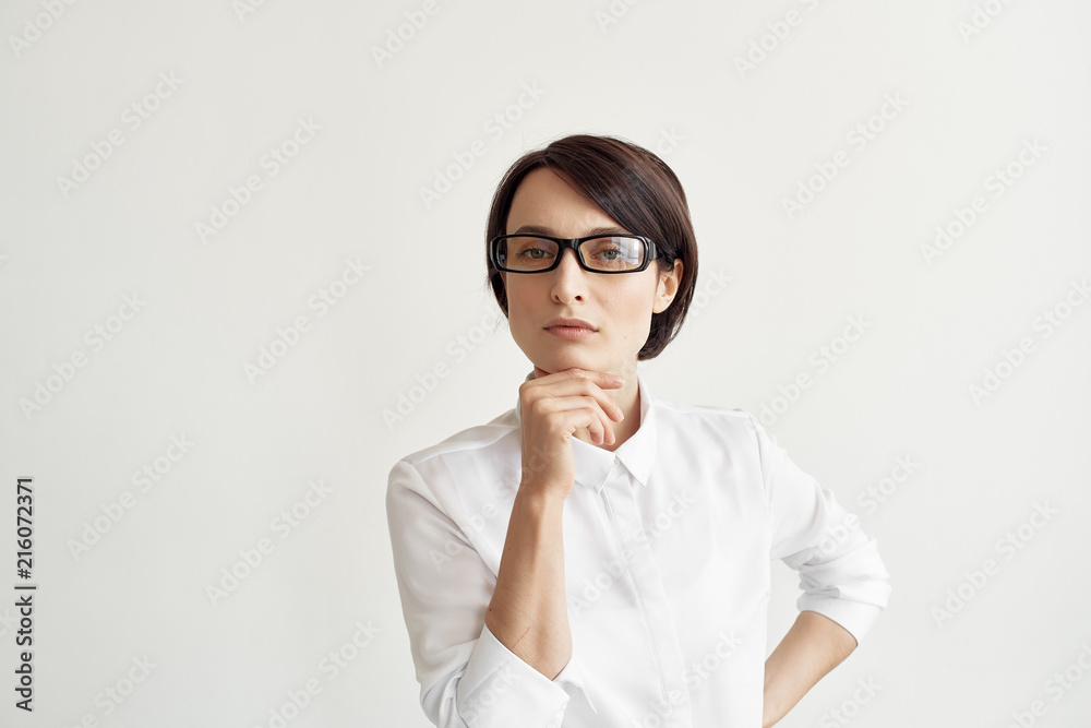 serious business woman with glasses thinks on a light background portrait