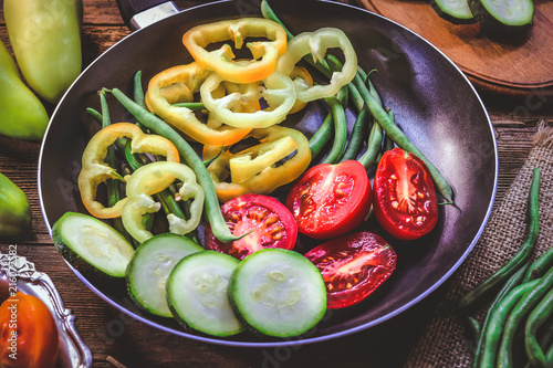 cut peppers, tomatoes and bean pods in a frying pan