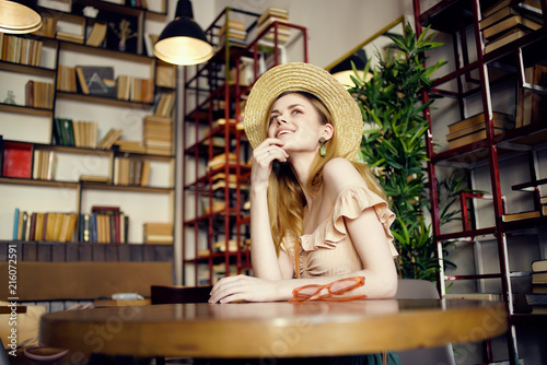 woman with hat is sitting in a cafe resting books