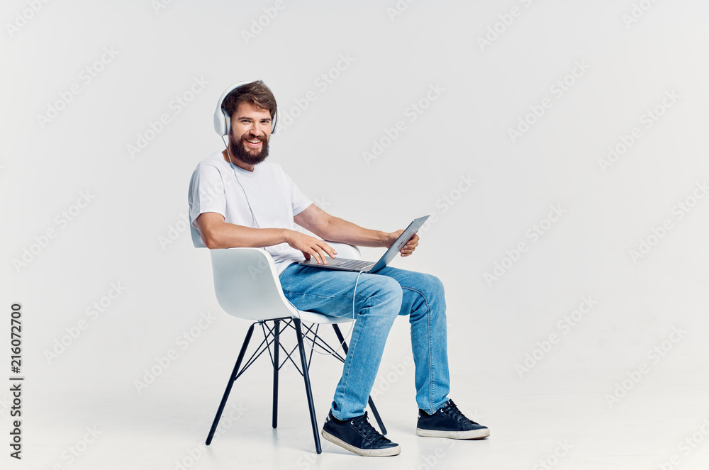 man sitting on a chair with a laptop with headphones