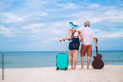 couple of traveler have a baggage and guitar standing on the beach.Asia tourist enjoying at the sea on vacation.