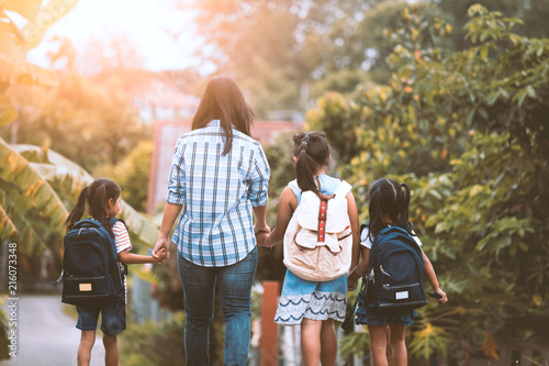 Back to school. Asian mother and daughter pupil girl with backpack holding hand and going to school together in vintage color tone photo