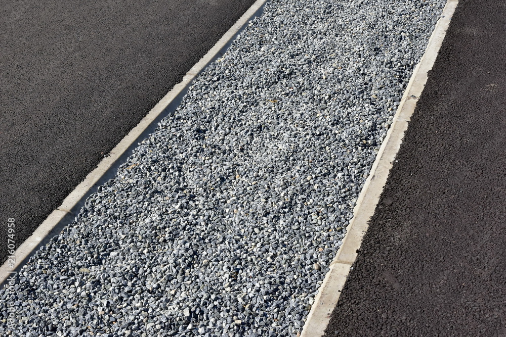 Fototapeta premium Crushed plot fenced with curb among asphalt pavement