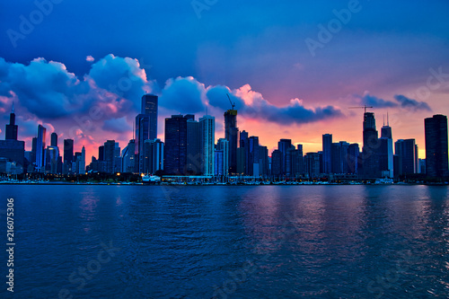 Sunset over city of Chicago create shadows of the skyline, seen from Lake Michigan during summer boat ride.