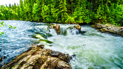 Large rocks split the water of the Murtle River as it drops over the Mushbowl Falls in Wells Gray Provincial Park in British Columbia, Canada photo