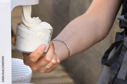 Female hand serving soft ice cream from a machine. © Ruben