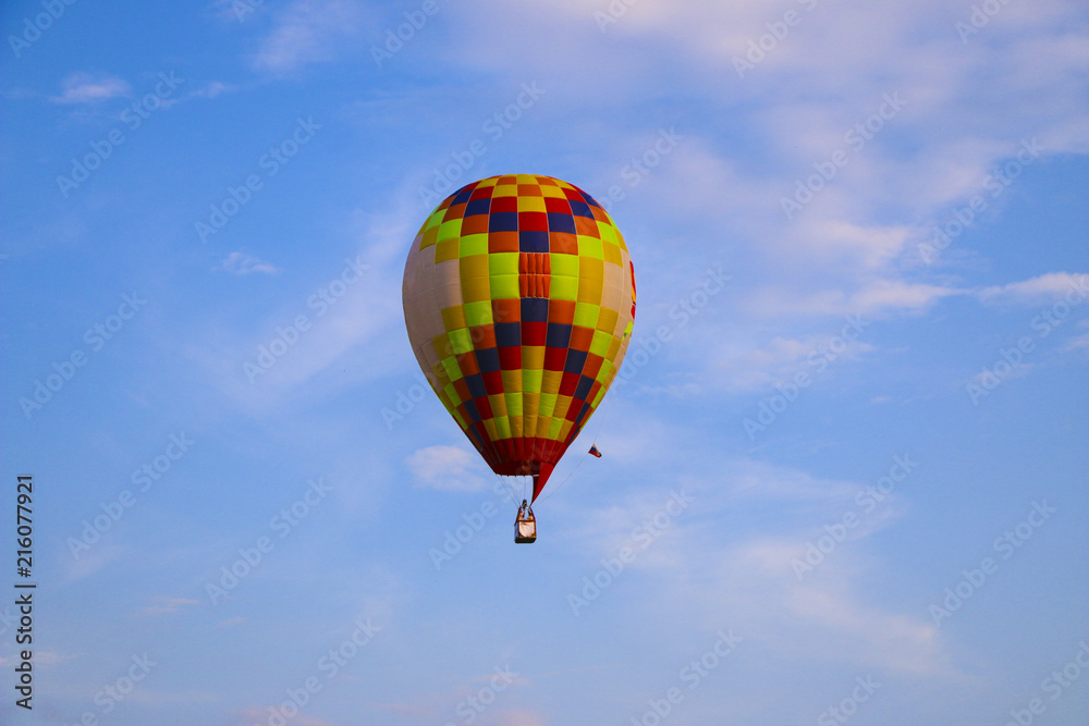colorful hot air balloon against blue sky. hot air balloon is flying in white clouds. beautiful flying on hot air balloon colorful hot air balloon against blue sky. hot air balloon is flying in white clouds. beautiful flying on hot air balloon