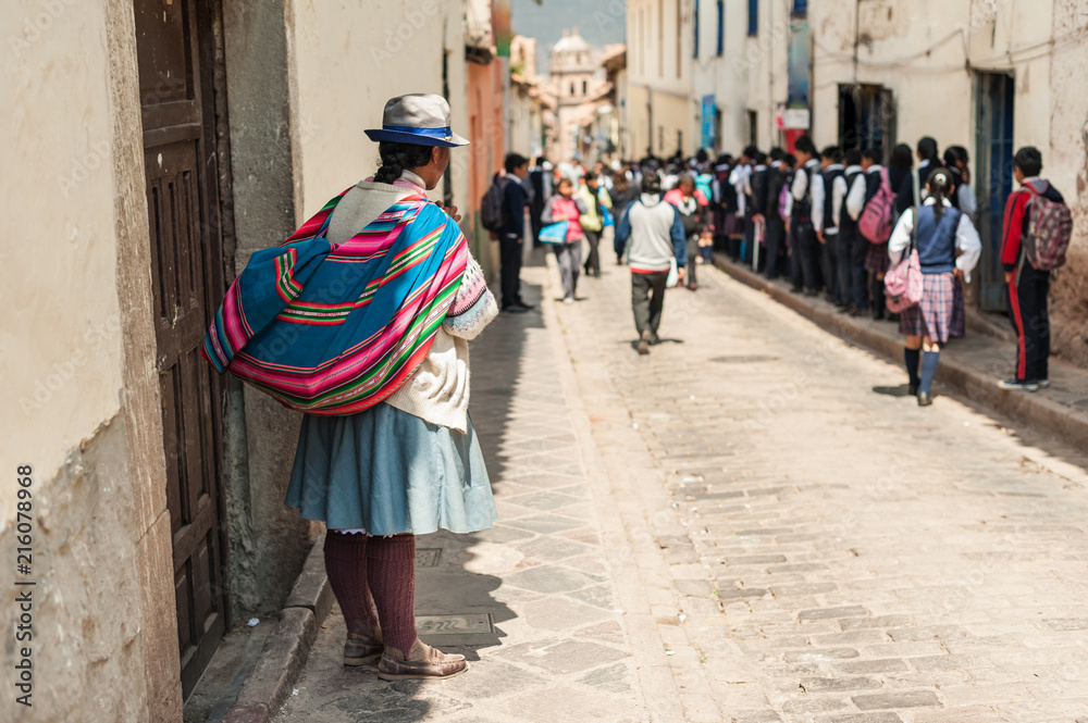Group of children heading to school in the morning. Wearing colorful traditional clothing, walking down the street in school uniforms in Cusco, Peru.