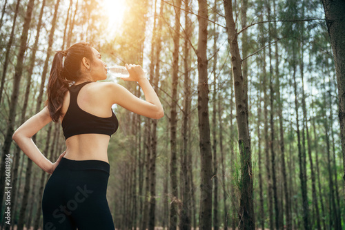 Asian girl is exercising at the weekend in a pine forest green and lush beautiful. Sport girl and lifestyle concept. She also playing yoga.