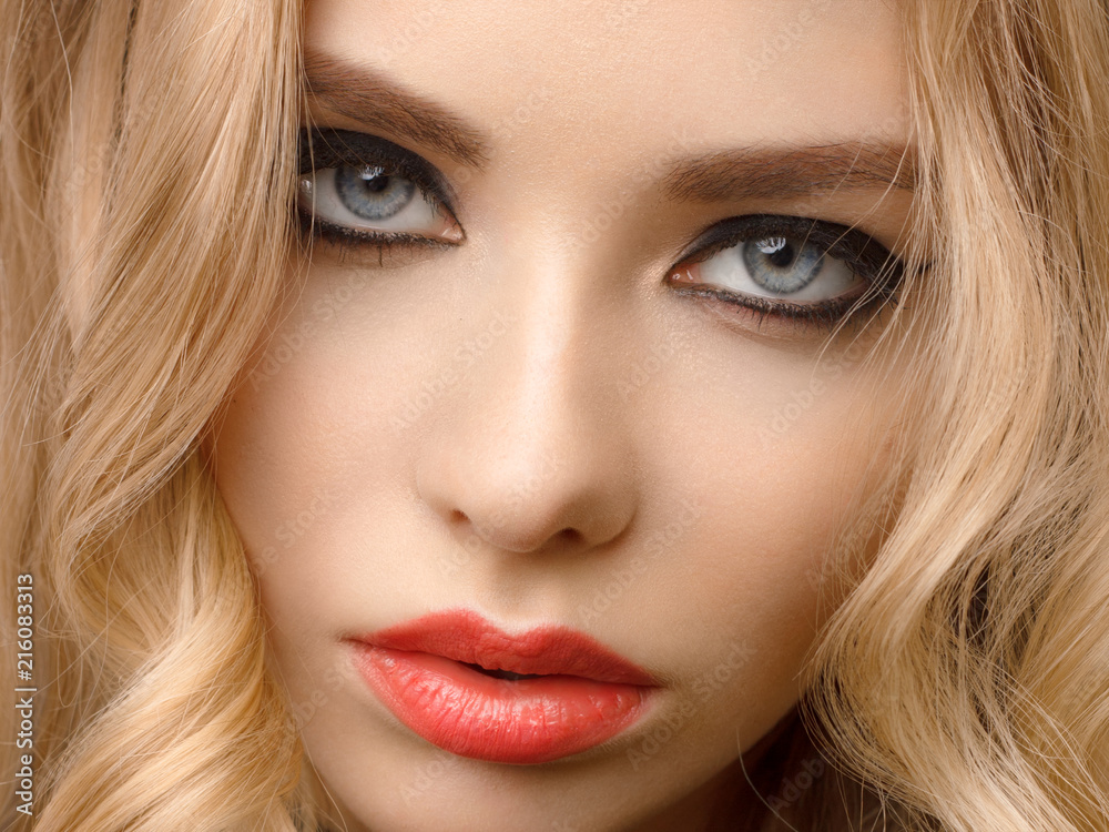 Glamour woman model with sexy evening make-up, curly blond hair, red lips and long eyeliner on eyes Glamour woman model with sexy evening make-up, curly blond hair, red lips and long eyeliner on eyes